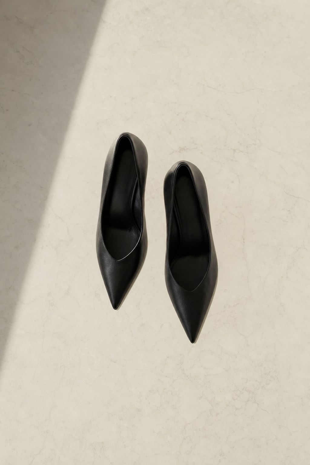 Black stiletto heels flat lay on pale marble